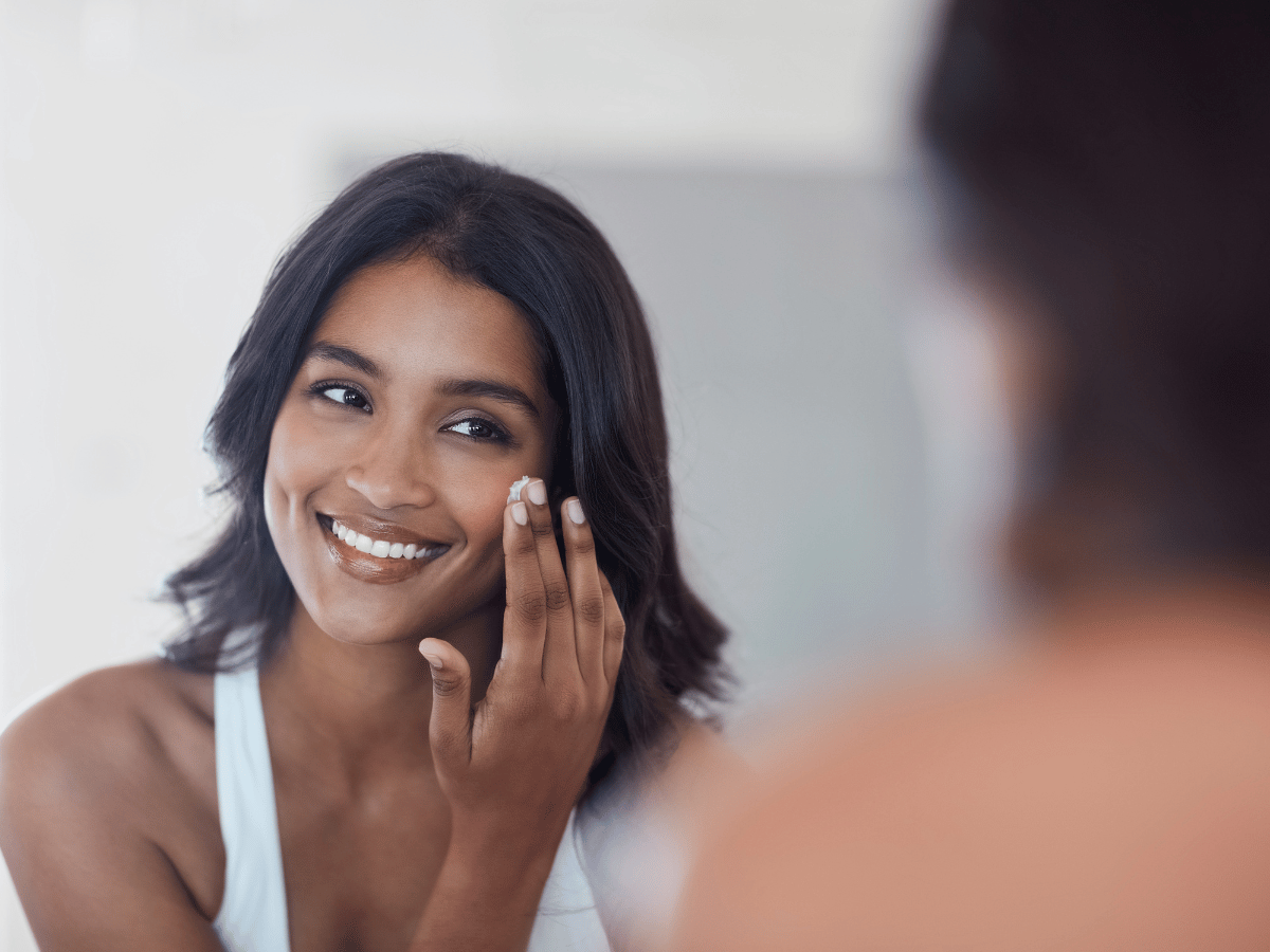 girl looking in mirror applying sunscreen